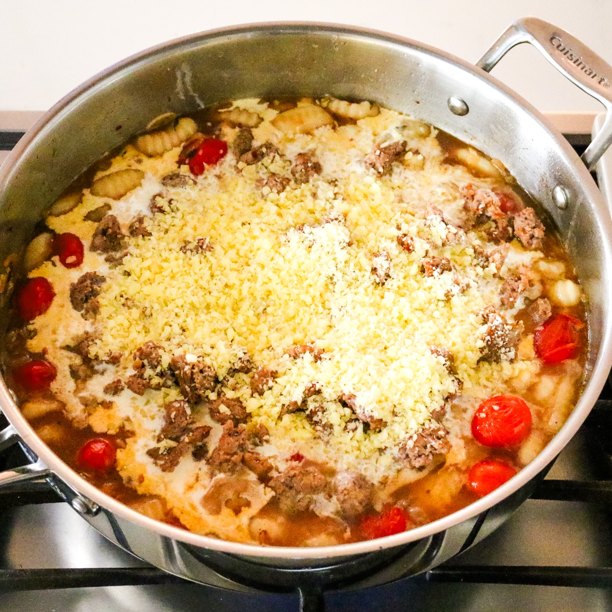 parmesan cheese added to a sausage and gnocchi and tomato mixture.