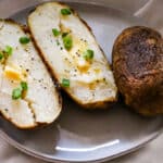 baked potatoes on a plate with butter and green onions.