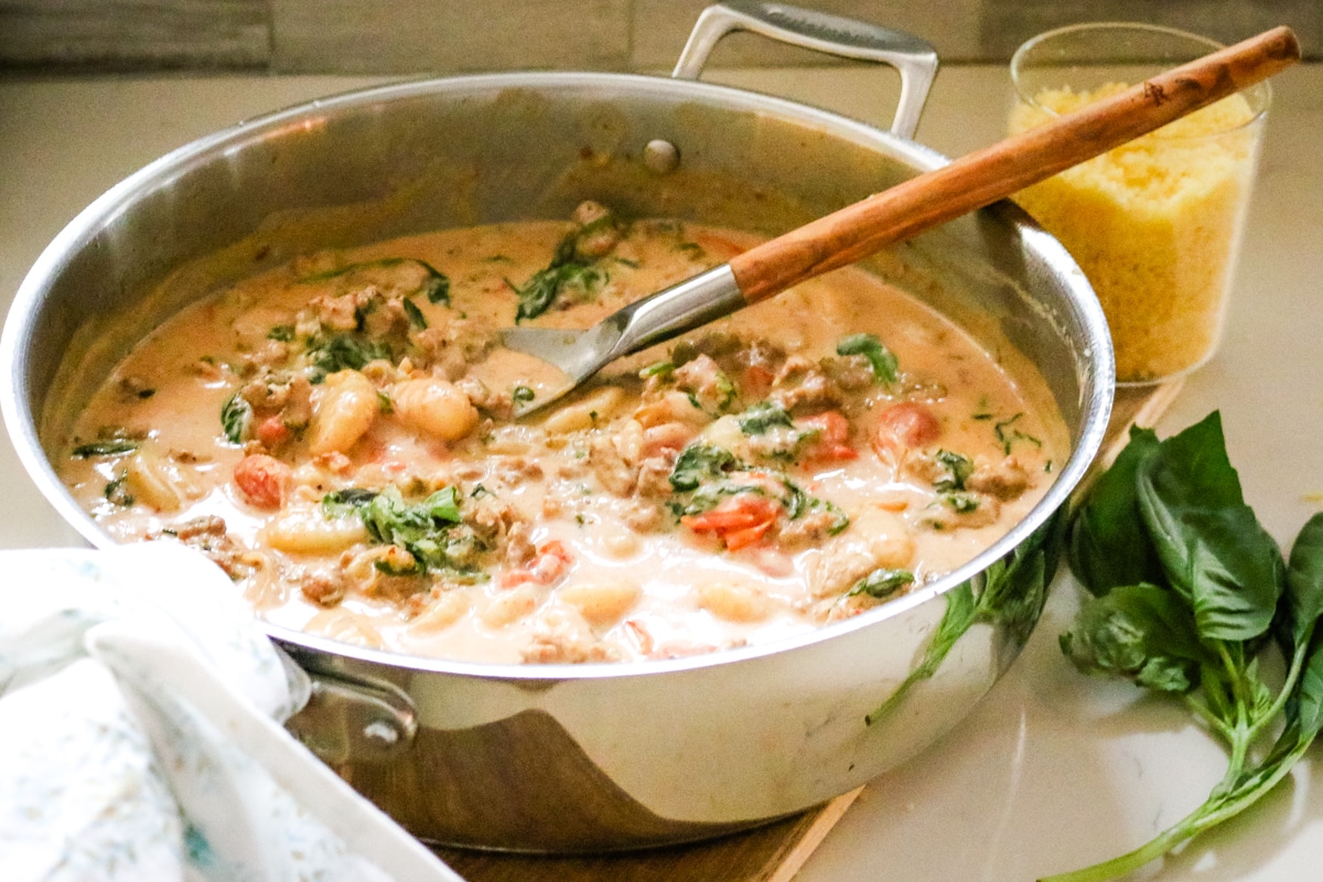 creamy sausage and gnocchi in a stainless steel pan.
