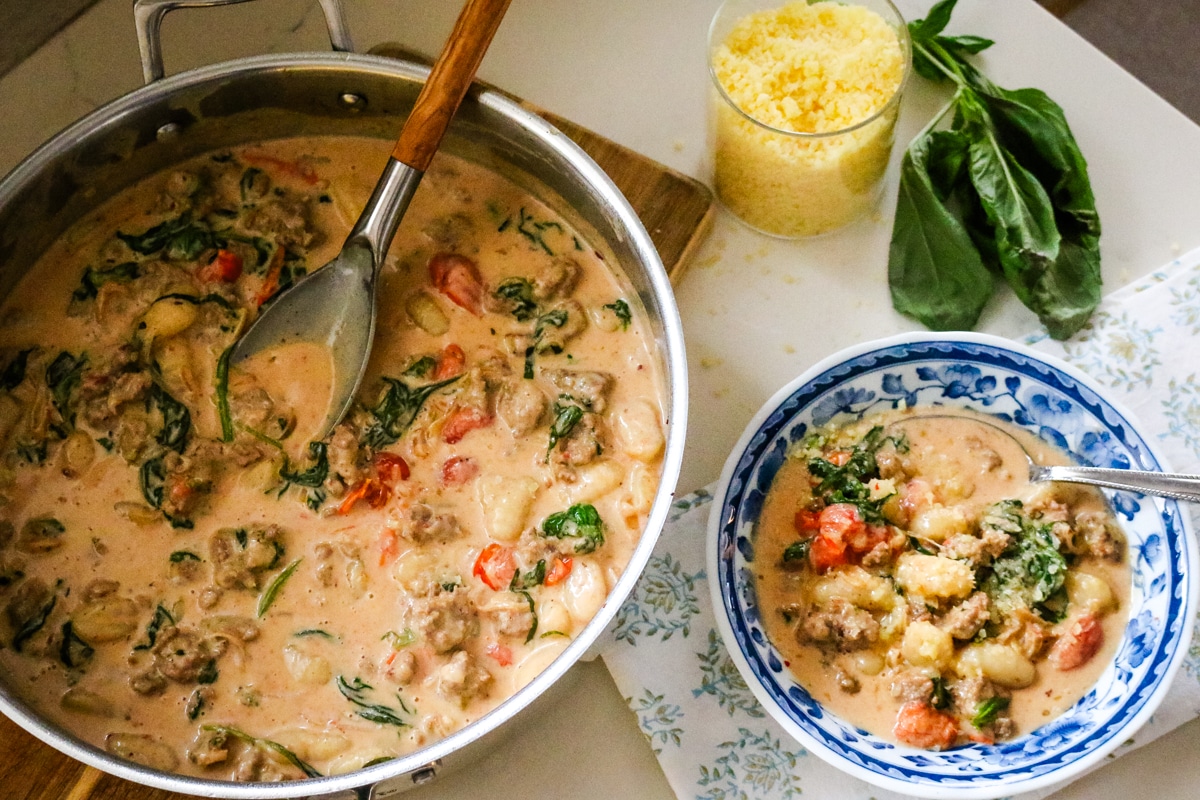 creamy sausage and gnocchi with tomatoes in a pan and bowl.