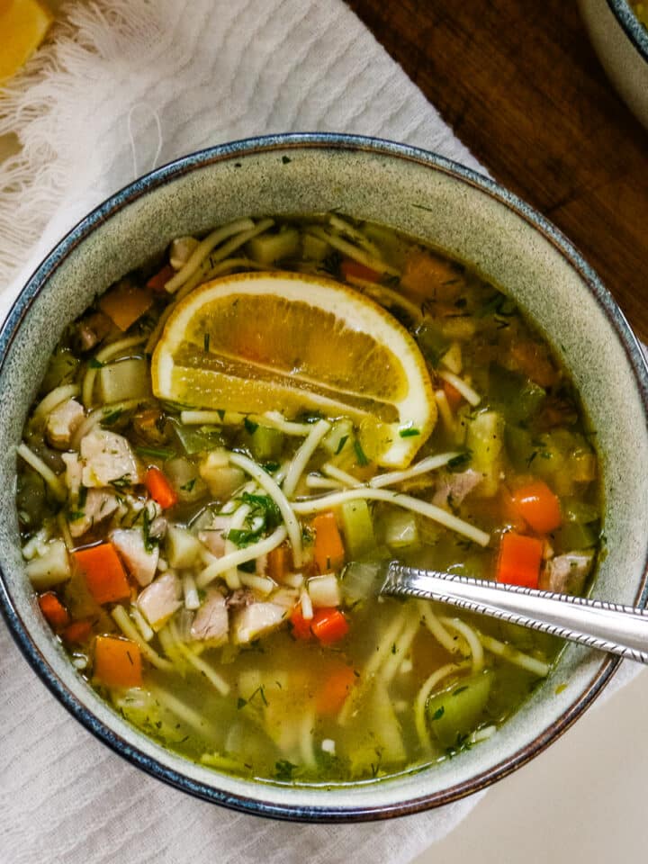 Romanian ciorbă soup served in a bowl with a spoon.