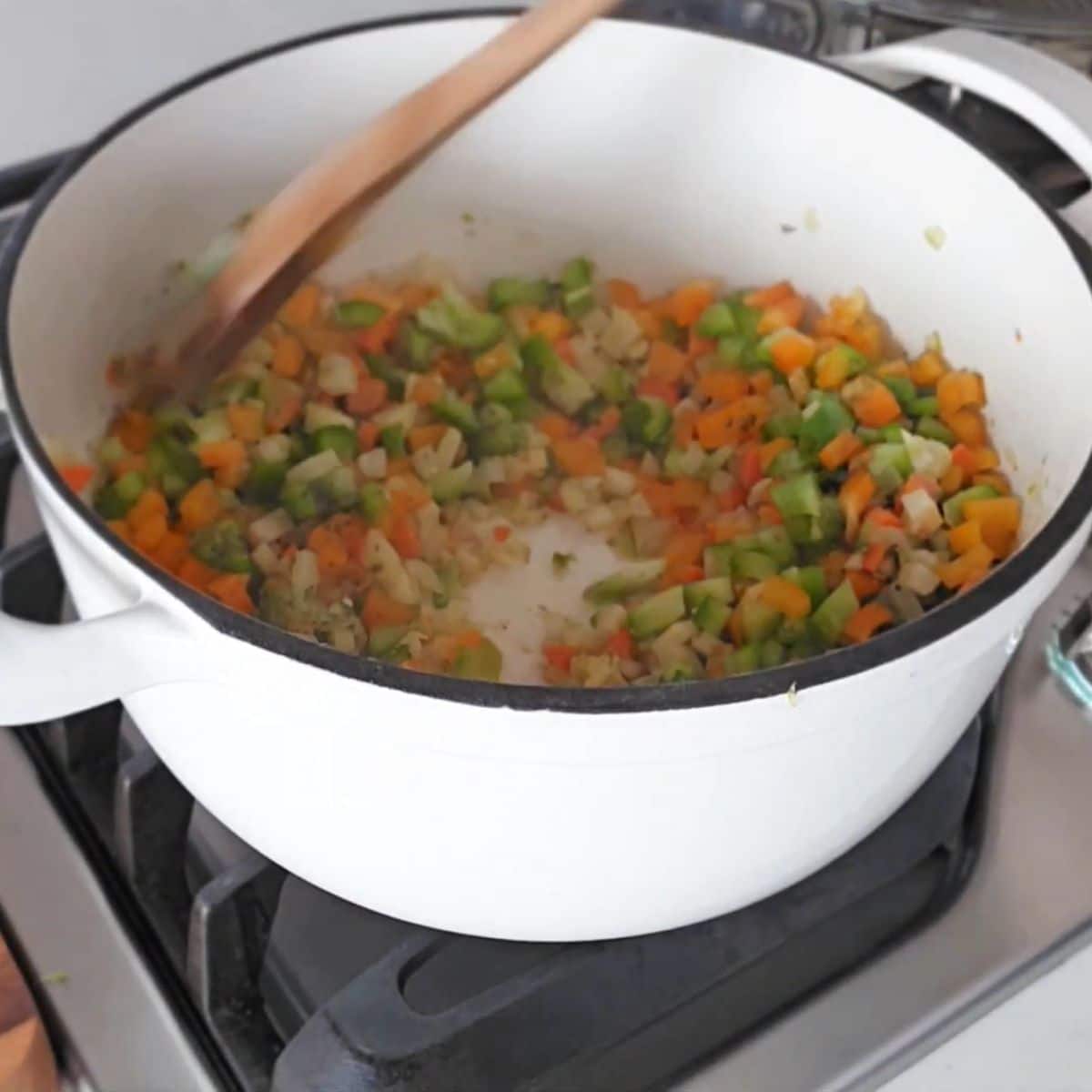 Diced orange and green bell peppers added to sautéed vegetables.