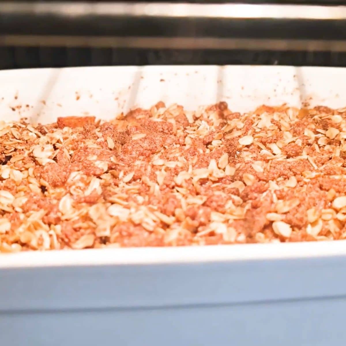 Apple crisp baked until golden and bubbling, cooling before serving with vanilla ice cream.