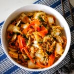 Thinly sliced napa cabbage and shaved carrots tossed together in a fresh, colorful salad, served in a bowl with a light dressing.