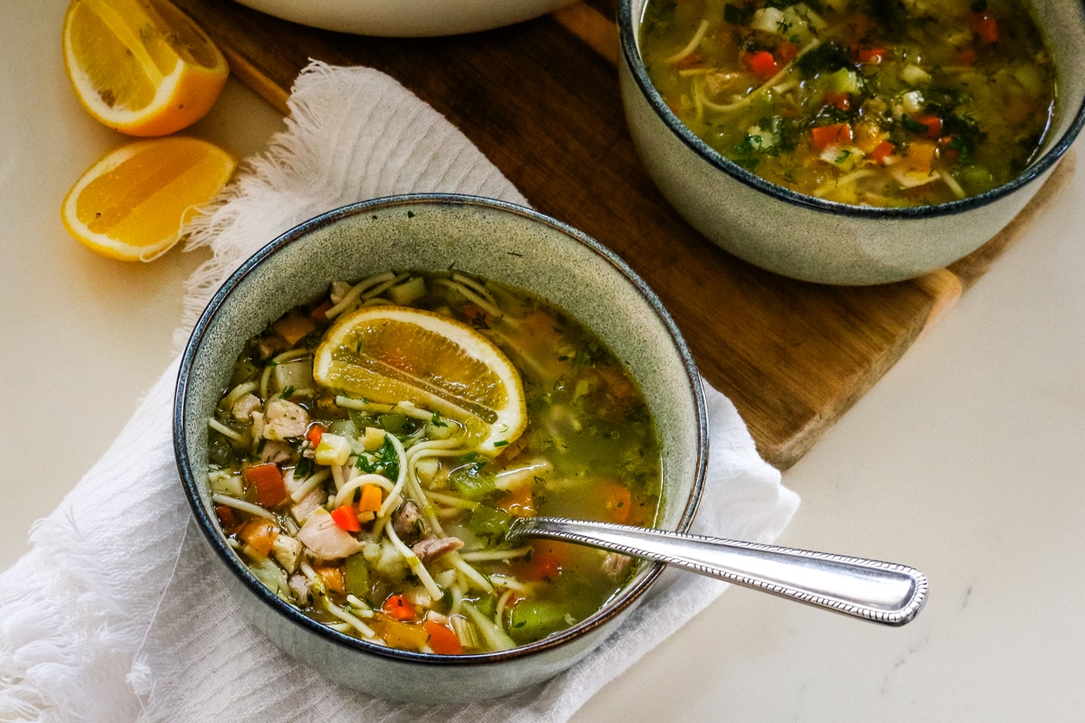 Romanian ciorbă soup served in a white pot and a white bowl.