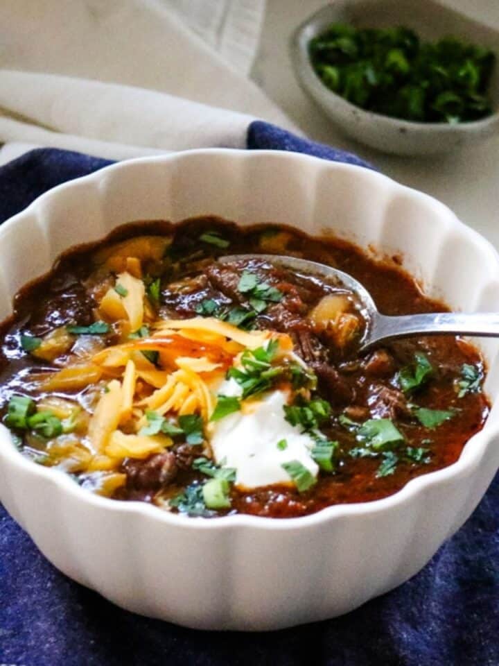 shredded beef chili with cilantro, shredded cheese, and sour cream.