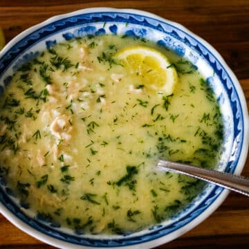 Avgolemono soup with lemon and shredded chicken, served with a spoon.