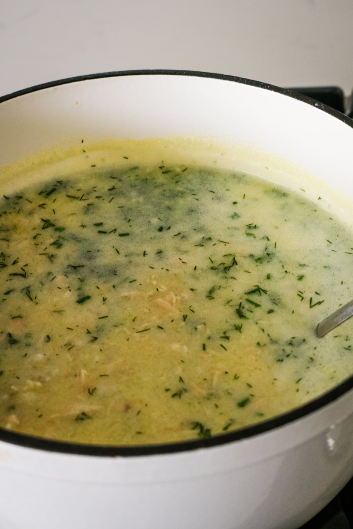 Avgolemono soup with a spoon.