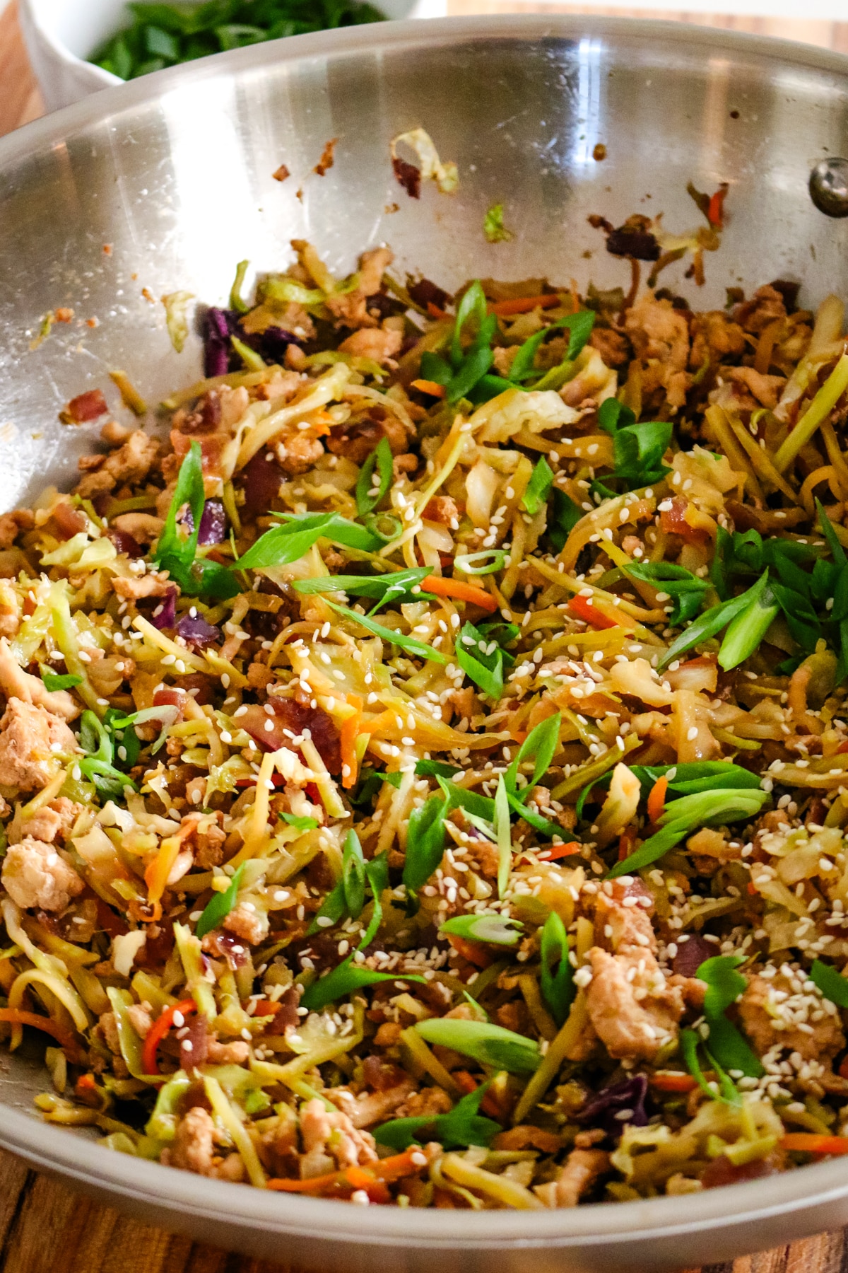 egg roll in a bowl in a large wok with green onions garnished on top.