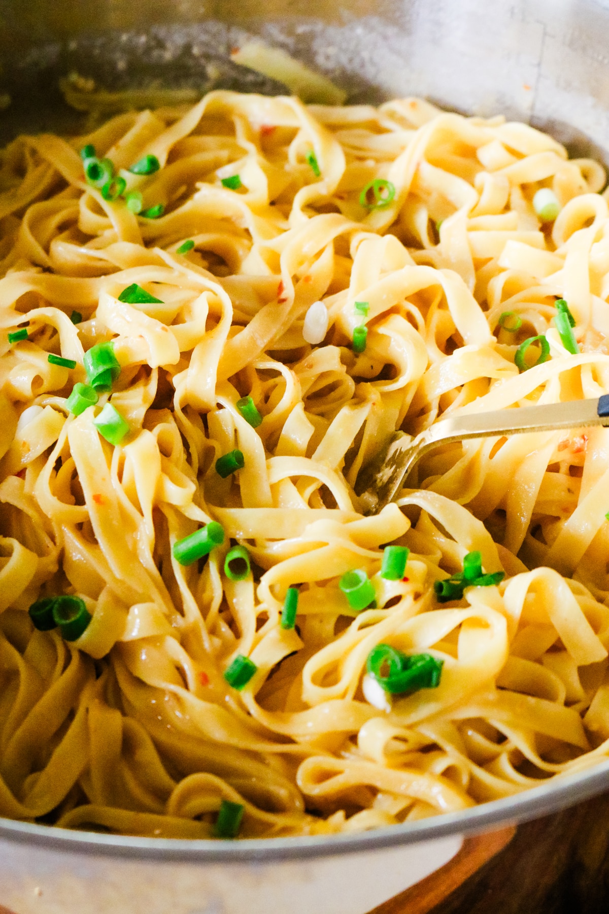 miso noodles with a spoon on the right side and scallions garnish.