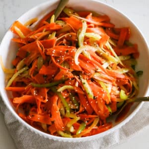 shaved carrot ribbons, thinly sliced celery and bell pepper in a white bowl.