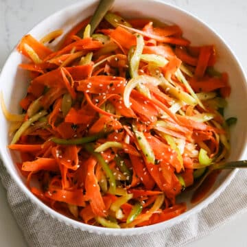 shaved carrot ribbons, thinly sliced celery and bell pepper in a white bowl.