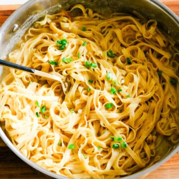 miso pasta in a stainless steel pan with green onions garnish.