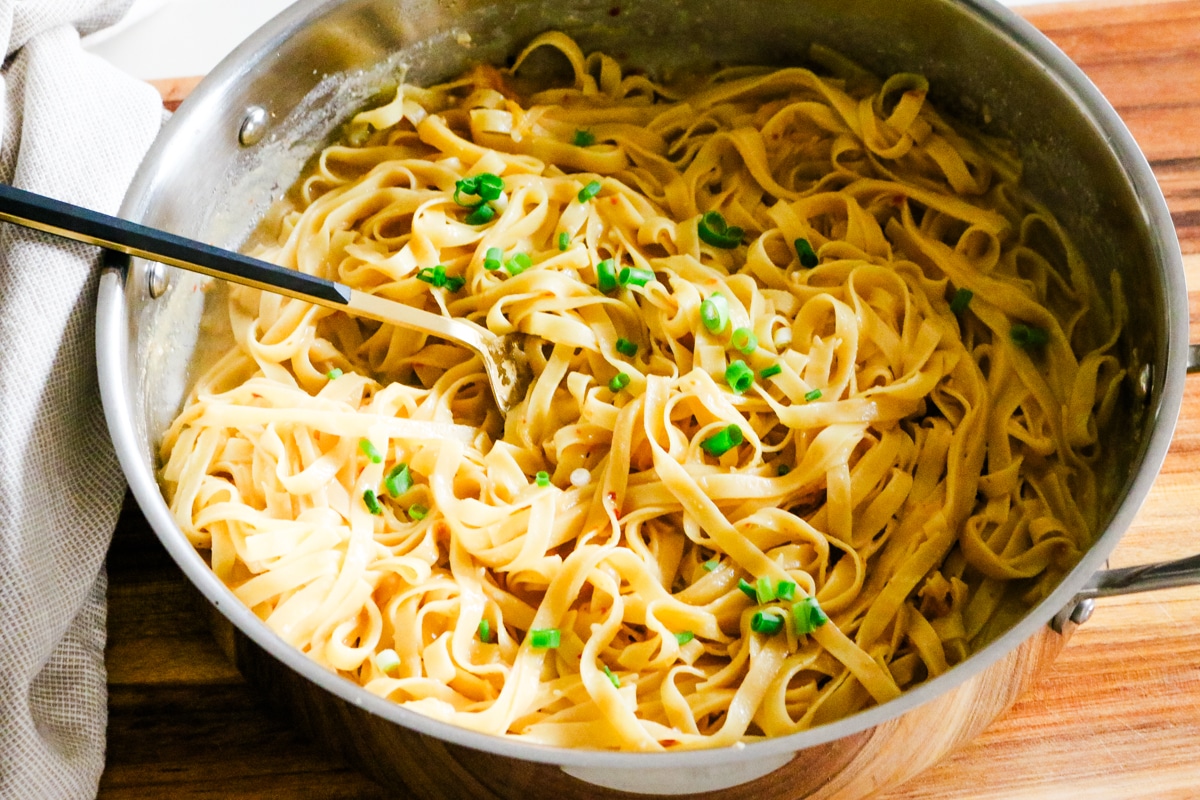 miso pasta in a deep pan on a wooden board with green onions.