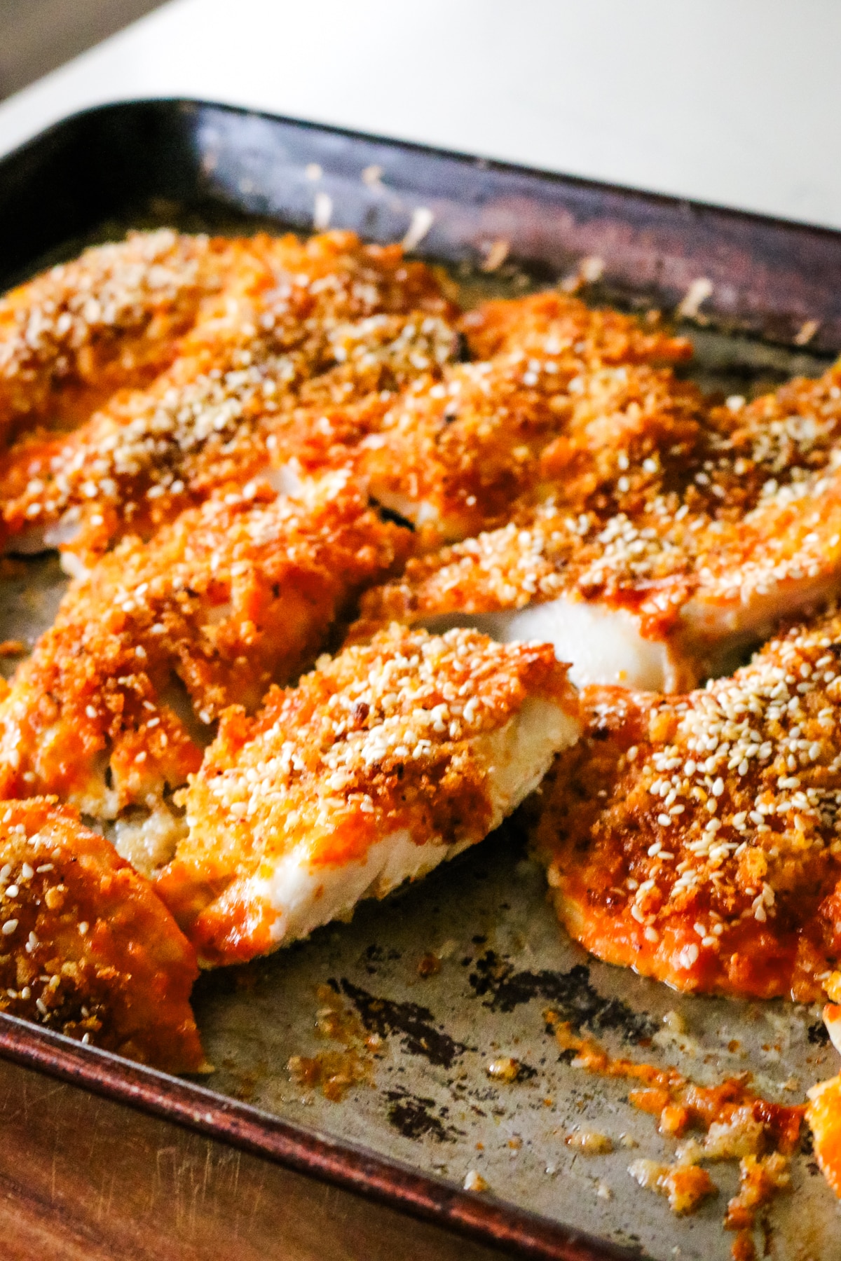 panko crusted with sesame seeds fish on a sheet pan.