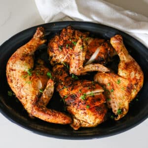 dry brine chicken on black platter with parsley garnish