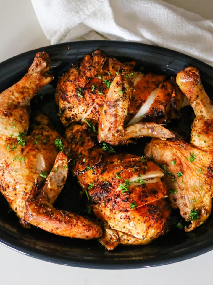 dry brine chicken on black platter with parsley garnish