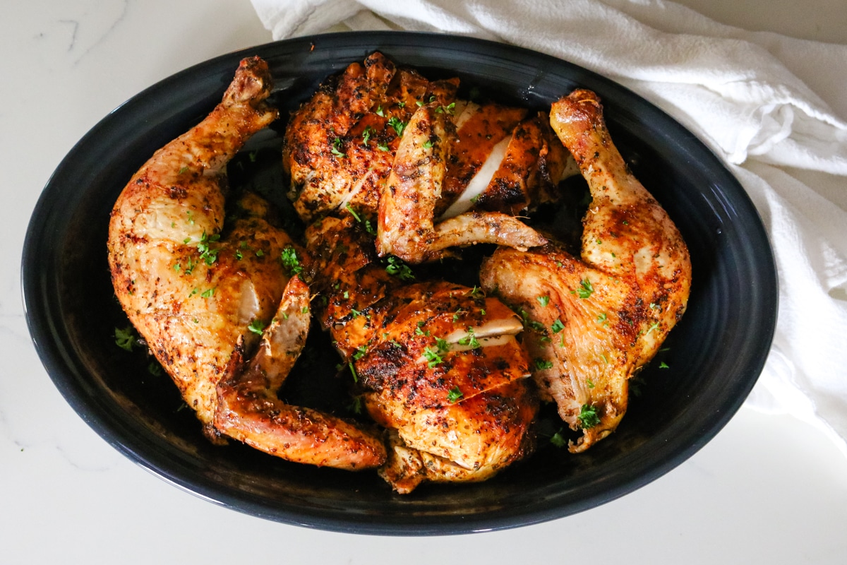 roast chicken carved in a black platter.
