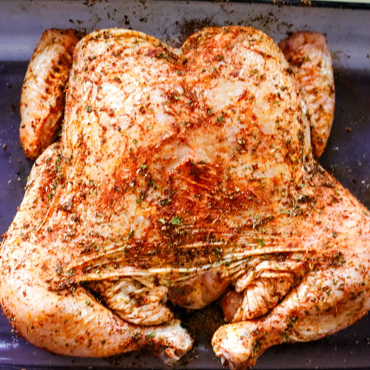 roast chicken seasoned in a baking sheet.
