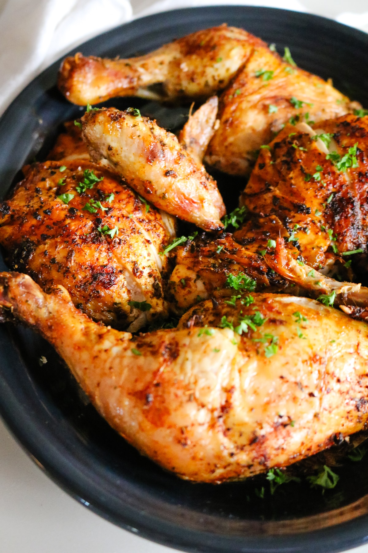 dry brine chicken on black platter with parsley garnish.
