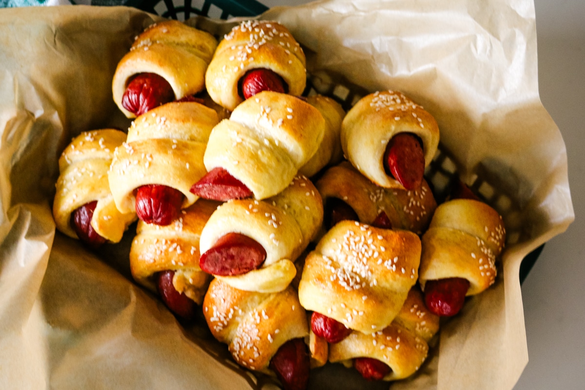 pigs in a blanket on parchment paper in a tray.