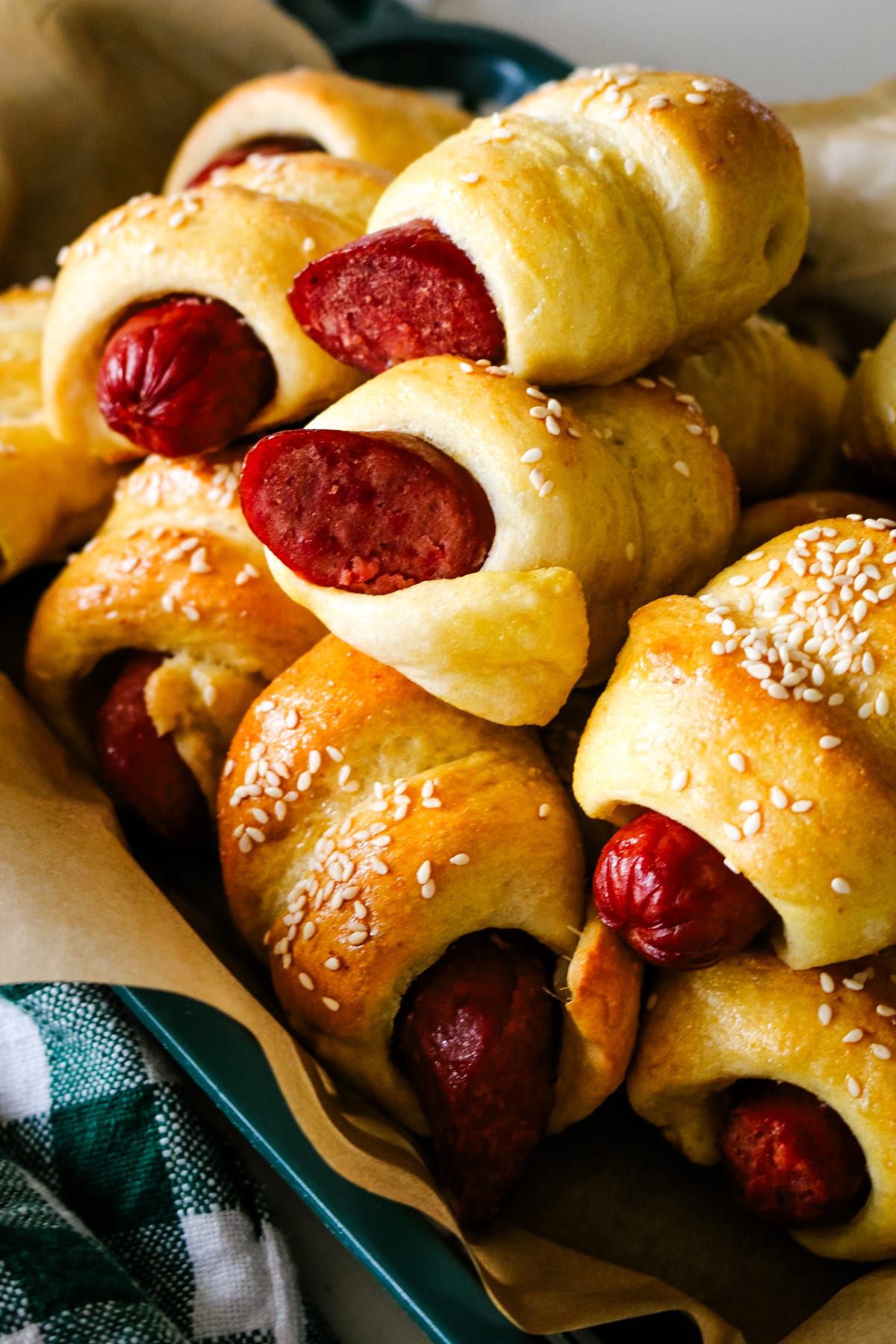 closeup of pigs in a blanket on parchment paper in a tray.
