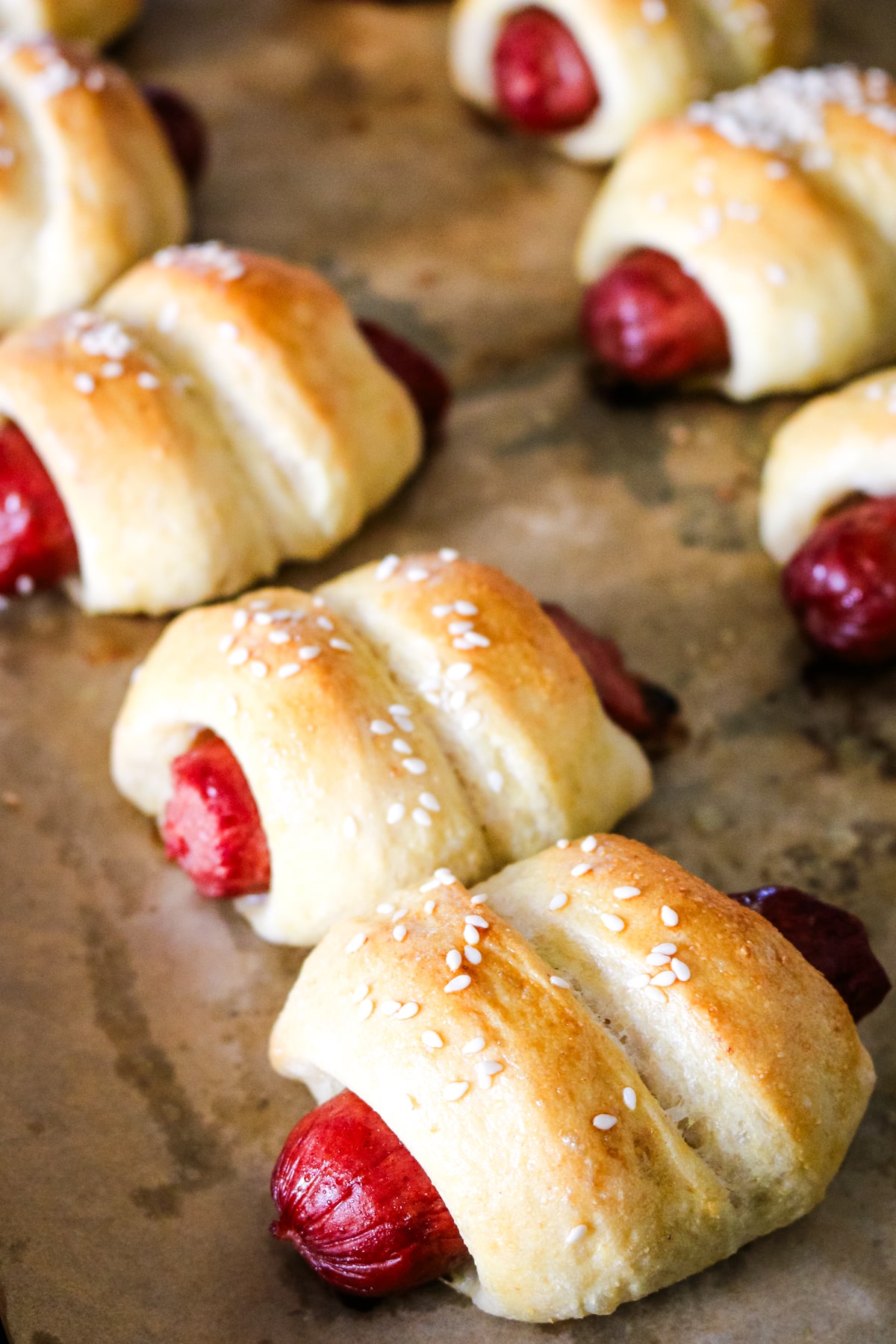 pigs in a blanket on parchment paper on a metal pan.