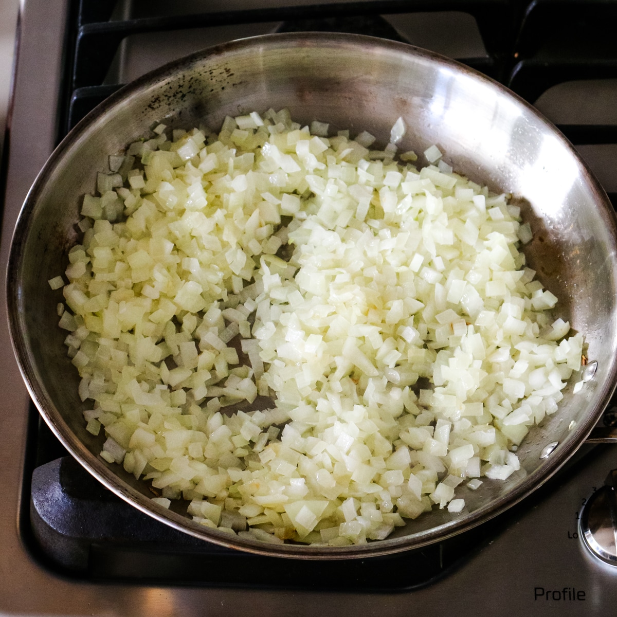 sauteed diced onions in a stainless steel pan.