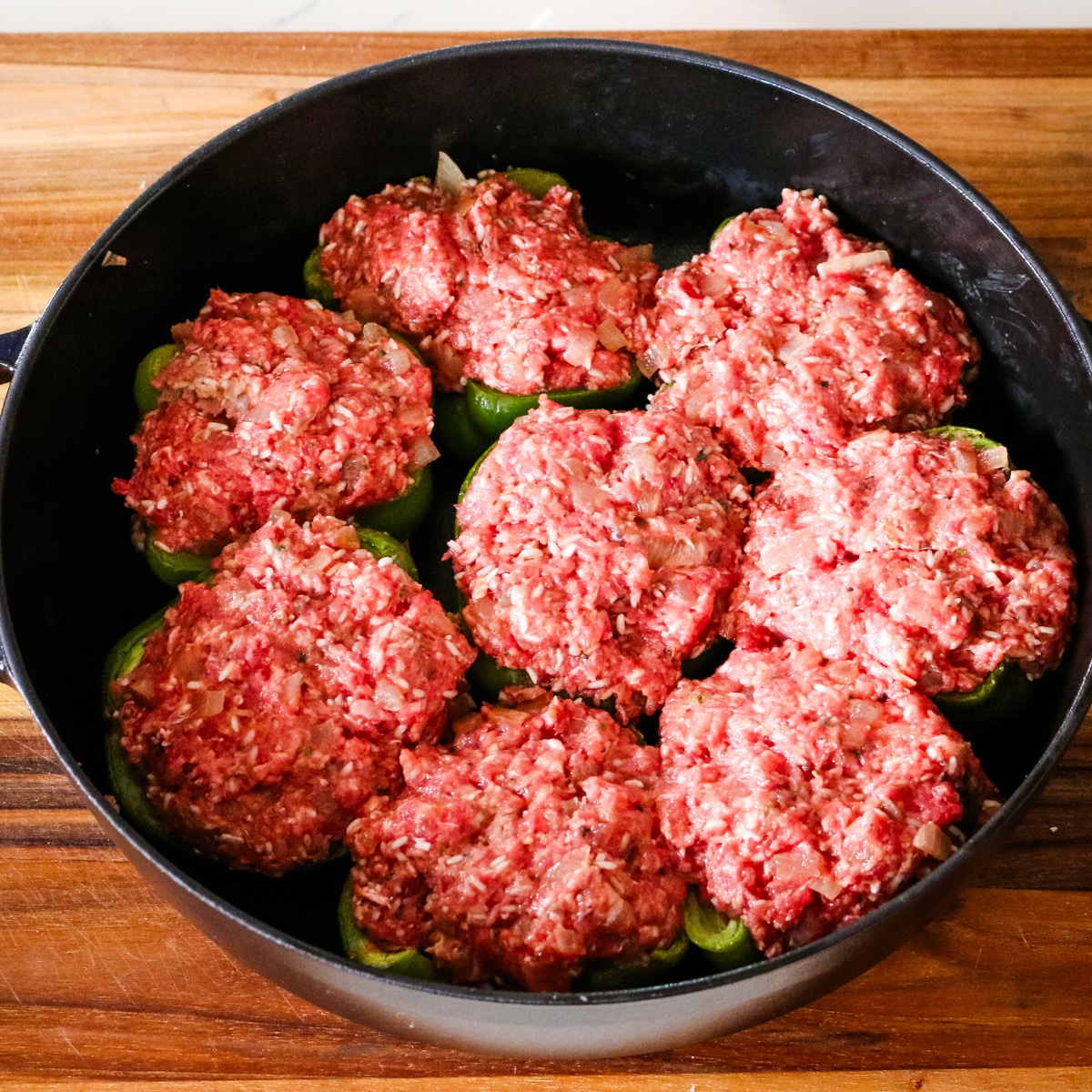 uncooked stuffed bell peppers in a deep saute pan.