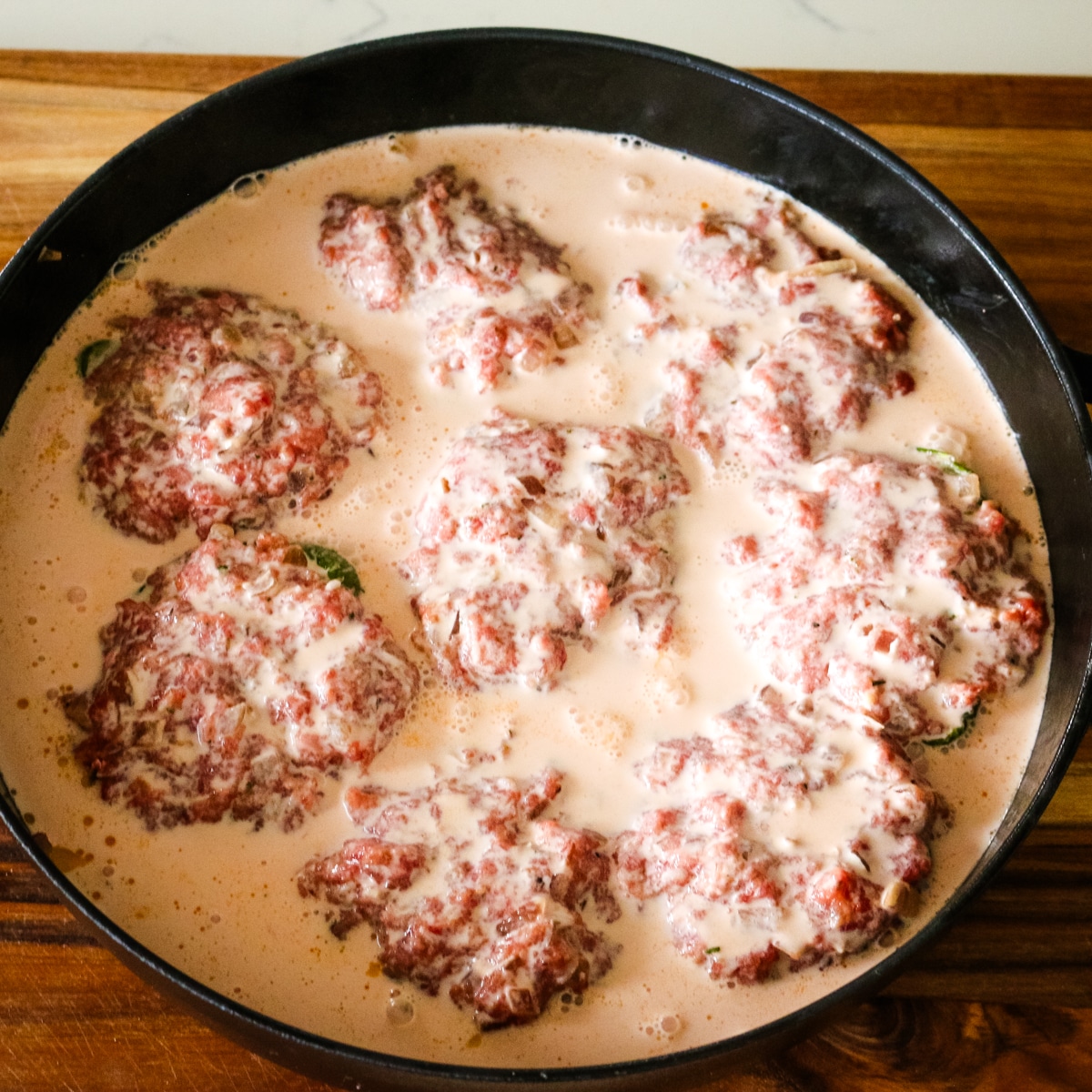 creamy tomato mixture in a pan with stuffed green bell peppers.