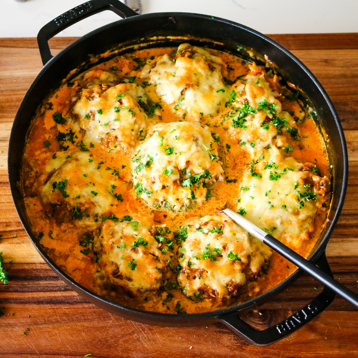 stuffed bell peppers in a creamy tomato sauce in a deep dish pan.