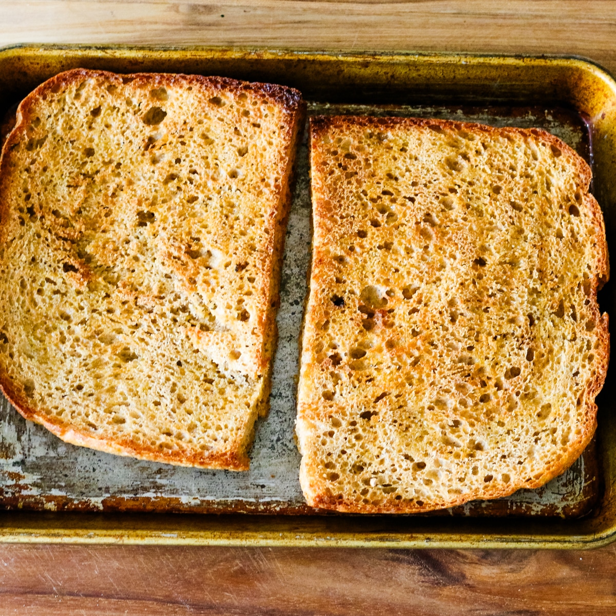 Two toasted slices of bread on a metal baking pan.