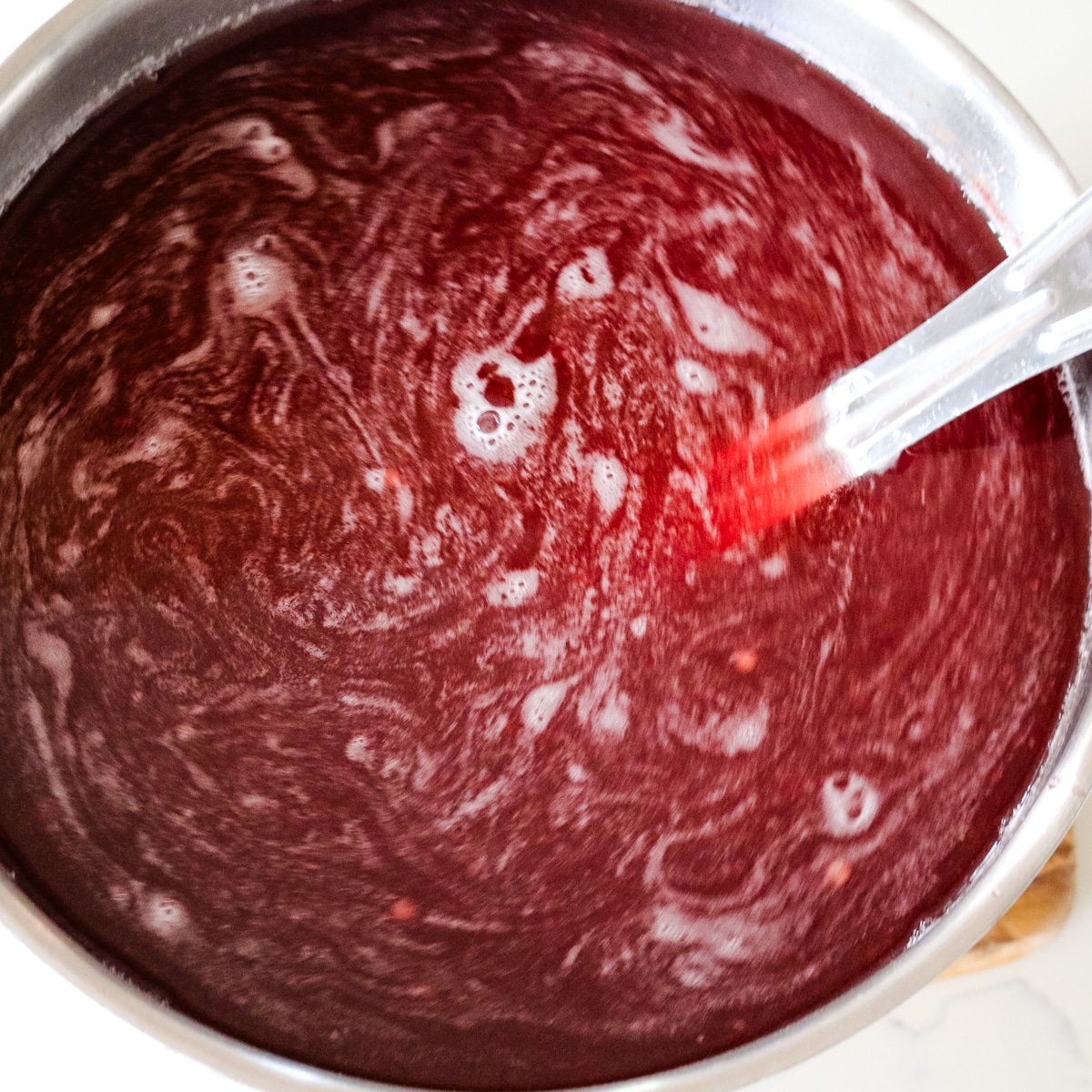 Stirring strained kompot in a metal pot.
