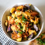 parmesan crusted potatoes in a white bowl, garnished with fresh parsley.