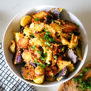 parmesan crusted potatoes in a white bowl, garnished with fresh parsley.