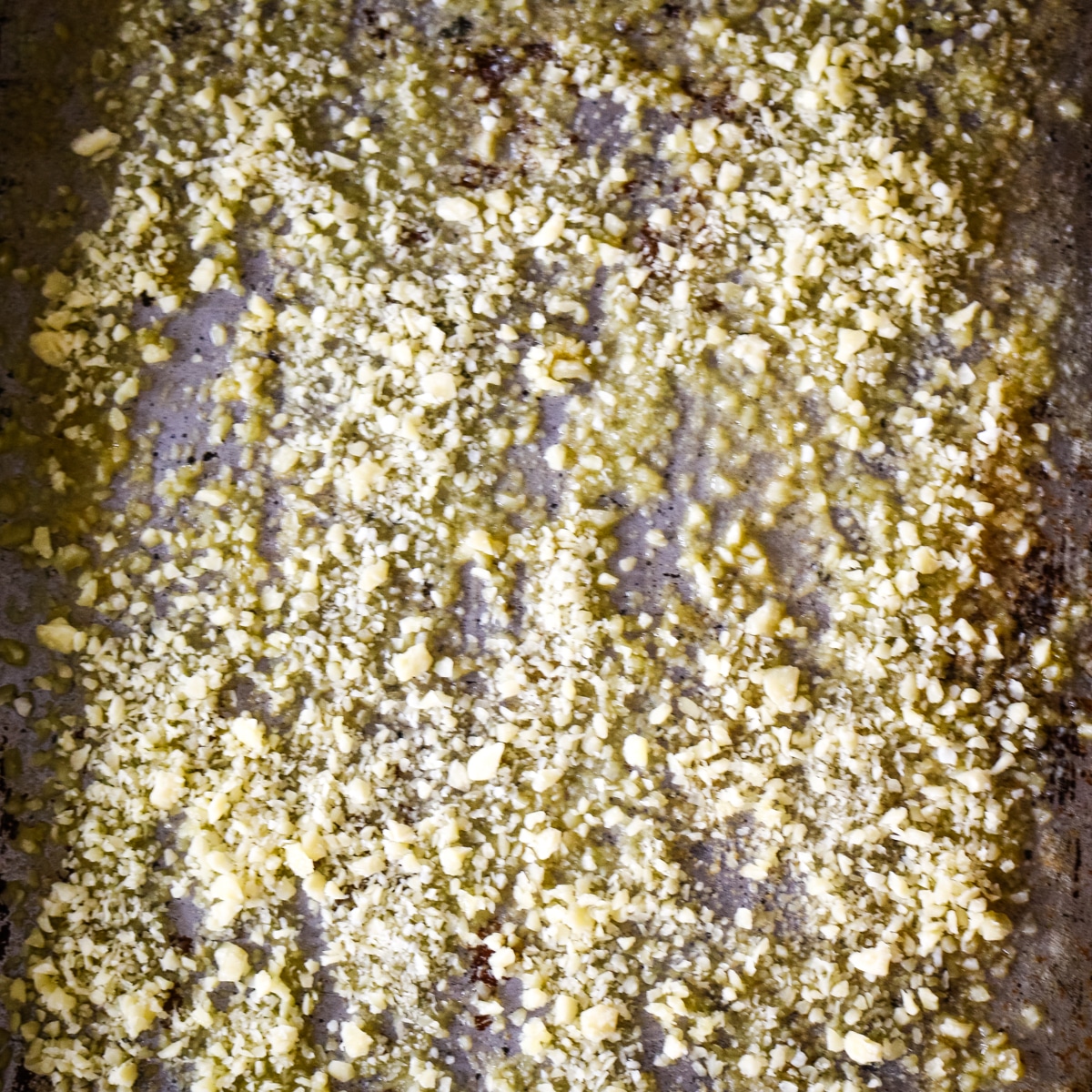 Grated parmesan cheese, oil, and seasonings arranged on a metal baking tray, ready for roasting.