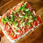 smoked salmon sushi with rice, green onions, and spicy mayo drizzled on top.