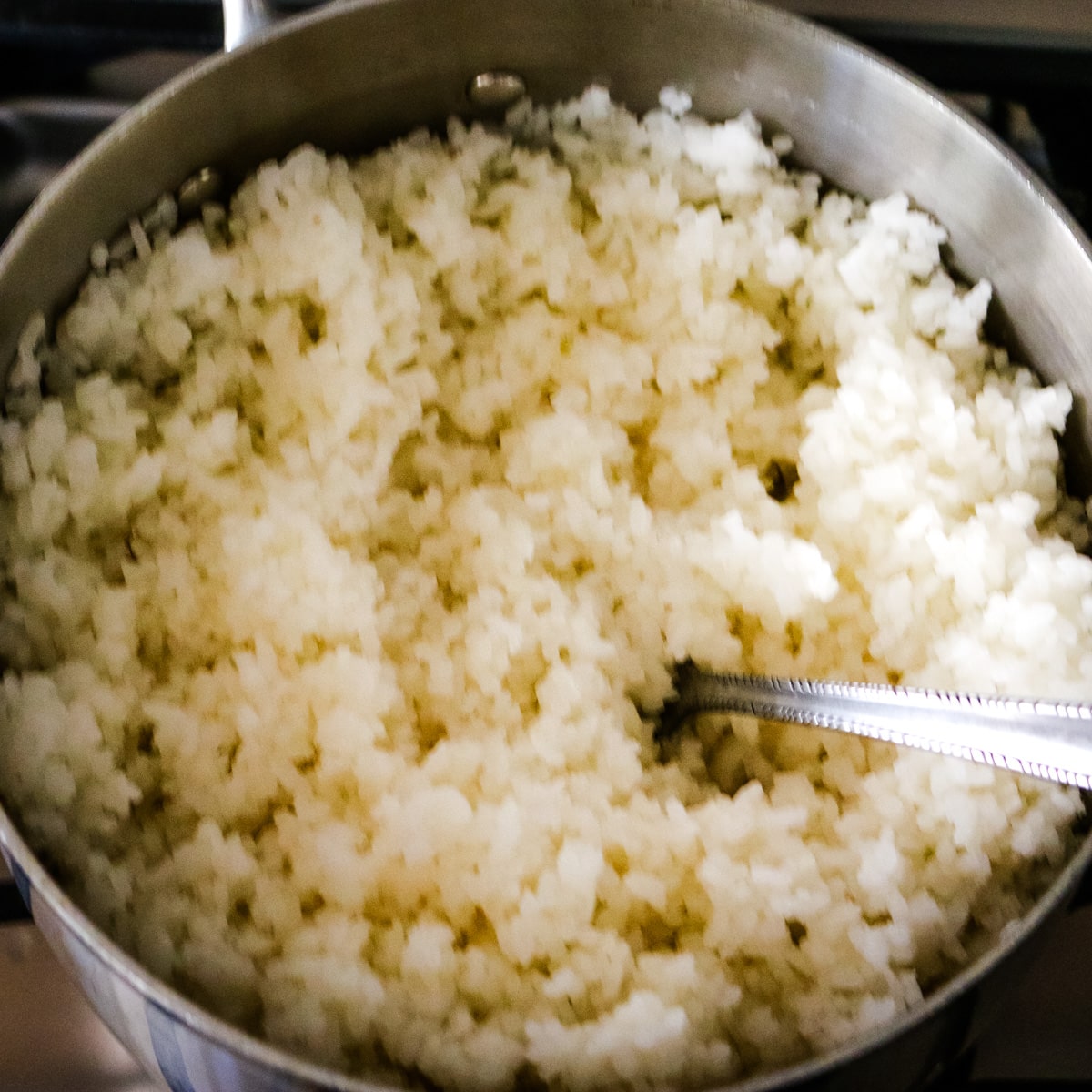 rice being cooked in metal pot in preperation to make smoke salmon sushi.