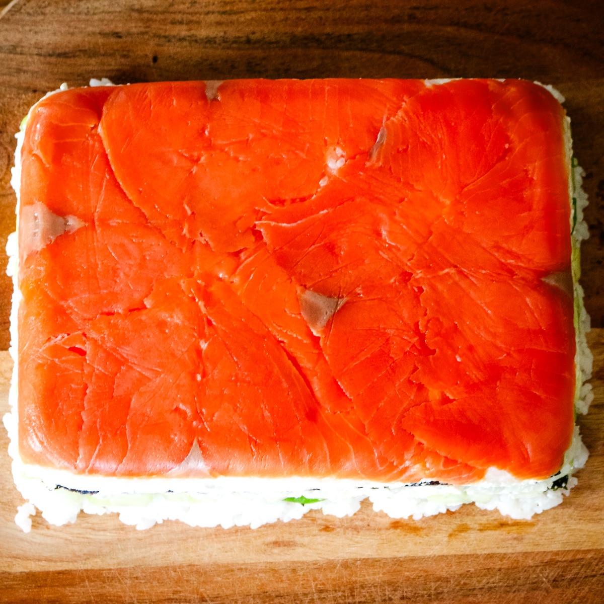 smoked salmon sushi that is ready to be cut into cubes.