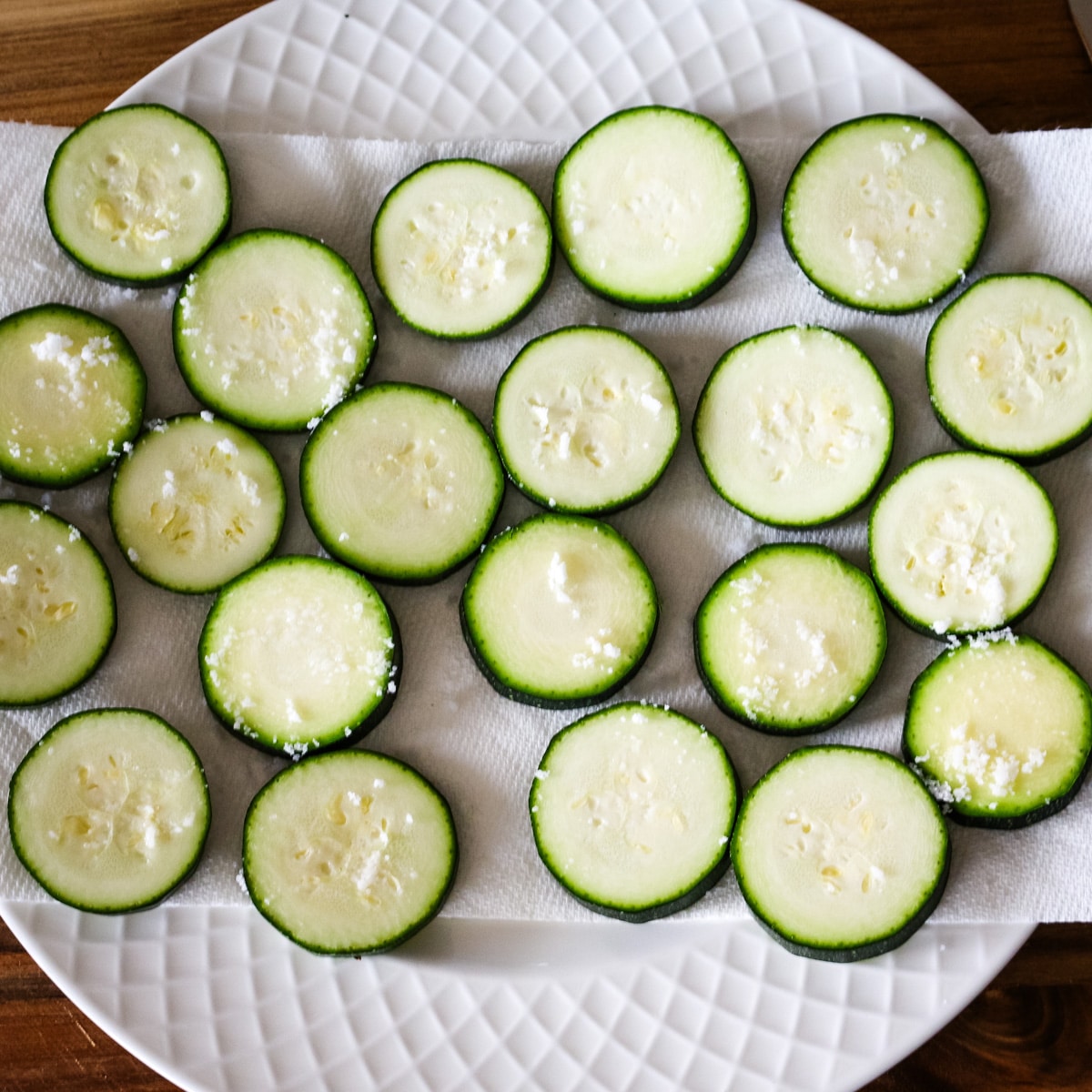 uncooked zucchini on a plate topped with salt.