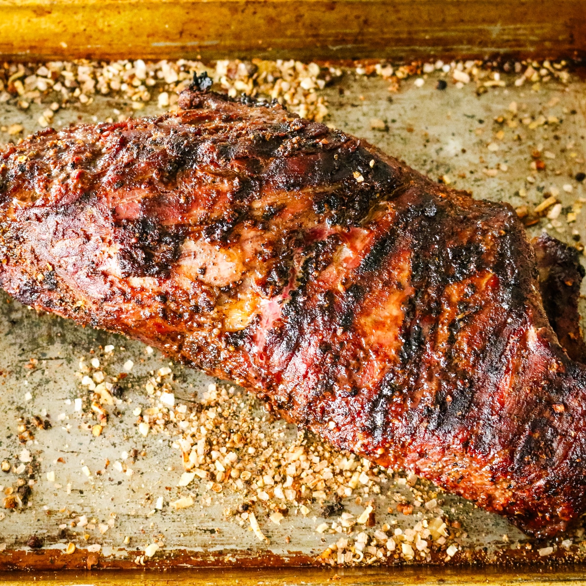 grilled seasoned steak on a metal pan.